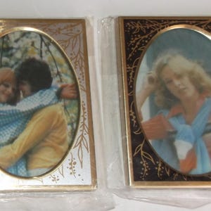 May include: Three rectangular picture frames with oval openings, each individually wrapped in clear plastic. Two frames have dark brown borders with gold floral patterns, while the center frame has a silver border with gold leaf designs.