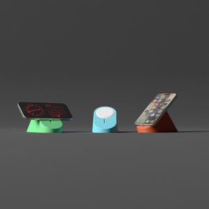 May include: Three tech accessories: a black device with a red display on a green stand, a blue charging dock, and a smartphone on an orange stand. All are set against a gray backdrop.