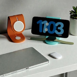 May include: An orange and white wireless charging stand and a teal phone stand with a watch holder. A laptop, a white mouse, and a desk lamp are also visible. The phone displays the time 11:03.