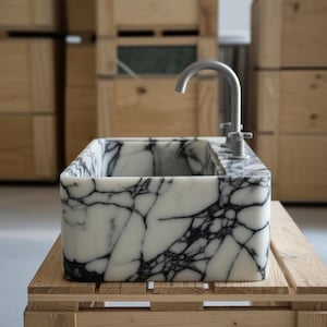 a marble-like sink with a silver faucet, placed on a wooden pallet.