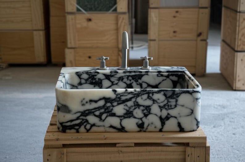 a marble-like sink with a black and white pattern, sitting on a wooden crate.