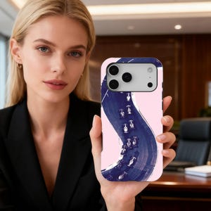 May include: A smartphone case with a pink background and a dark blue, abstract road design with small white cars. The case has a silver camera module. The case is held by a person.
