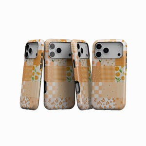 May include: Four phone cases with a patchwork design in shades of orange, white, and cream. The cases feature patterns like gingham, floral, and orange slices. The cases have a camera cutout and black side buttons.