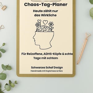 May include: A beige clipboard with a brown frame, featuring a black and white illustration of a brain with flowers and a heart. The text "Chaos-Tag-Planer" is at the top, followed by "Heute zählt nur das Wirkliche" and "Für Reizoffene, ADHS-Köpfe & echte Tage mit echtem". The bottom of the clipboard reads "Schwarzes Schaf Design Handmade mit Koptchaos & Herz".