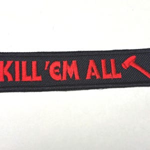 May include: A rectangular embroidered patch with a black background and a red border. The text KILL 'EM ALL is stitched in red capital letters, followed by a red graphic of a hammer positioned at an angle on the right side of the patch.