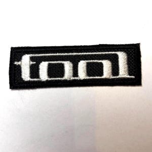 May include: Black embroidered patch with the word "TOOL" in white lettering.