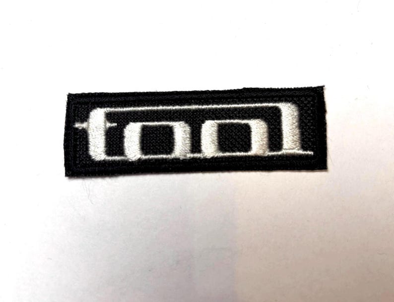 May include: Black embroidered patch with the word "TOOL" in white lettering.