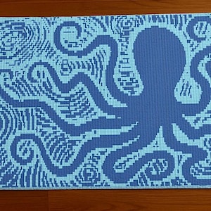 May include: A rectangular blue and light blue patterned rug featuring an octopus design. The octopus is a darker shade of blue, with its tentacles extending across the rug. The background has a wave-like pattern.