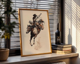 May include: A framed watercolor print depicts a cowboy riding a bucking bronco. The artwork features a brown horse and a rider in a hat, with a sepia-toned background. The print is displayed on a windowsill with a bottle of wine and books.
