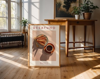 May include: A framed art print featuring a breakfast scene with churros and coffee. The print has the word "DESAYUNO" at the top and "MADRID" at the bottom. The artwork is in a room with wooden floors and furniture.