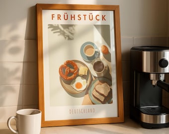 May include: A framed print with the word "FRÜHSTÜCK" and "DEUTSCHLAND" in orange text. The print depicts a breakfast scene with a pretzel, fried egg, coffee, and toast. A white mug and a coffee machine are on the counter.