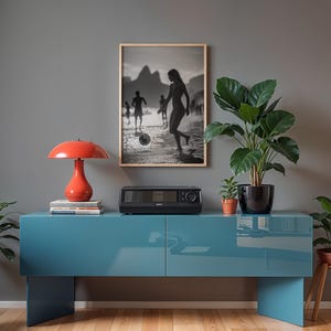 May include: A modern living room scene featuring a teal blue cabinet, a red mushroom-shaped lamp, and a black and white framed photograph. Potted plants and a small stereo system add to the decor.