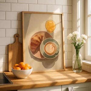 May include: A framed print depicting a breakfast scene with a croissant on a pink plate, a cup of coffee, and a glass of orange juice. A white bowl of oranges sits on a wooden countertop, next to a wooden cutting board and a vase of white flowers.