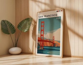 May include: A framed art print featuring the Golden Gate Bridge in San Francisco, USA. The artwork has a vintage travel poster style with the bridge in red, set against a blue sky and water. The print is in a wooden frame.