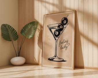 May include: A framed print featuring a martini glass with three 8-ball pool balls. The artwork is in black and white, with the words "feeling lucky?" written in cursive. The background is a light tan color.