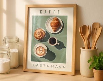 May include: A framed art print featuring a coffee-themed illustration. The print displays a croissant, a pastry, a cup of coffee, and a latte on a green background. The word "KAFFE" and "KØBENHAVN" are printed on the artwork.