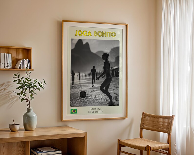 Może przedstawiać: Oprawiona czarno-biała fotografia osoby grającej w piłkę nożną na plaży. Obraz zawiera ż&oacute;łty napis "Joga Bonito" i brazylijską flagę. Fotografia jest w drewnianej ramie.