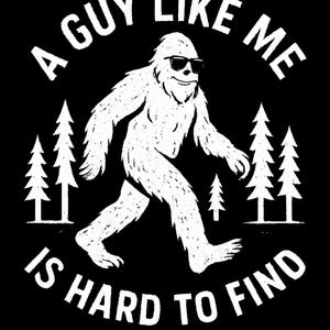 Op de afbeelding: Zwart grafisch t-shirt met een witte Bigfoot met een zonnebril, lopend met bomen aan weerszijden. De tekst luidt "A Guy Like Me Is Hard To Find" in een cirkelvormig ontwerp.