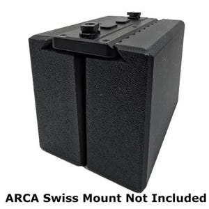May include: Black rectangular box with a textured surface and a black metal plate on top. The plate has a small knob on the right side and a larger knob on the left side.  ARCA Swiss Mount Not Included.