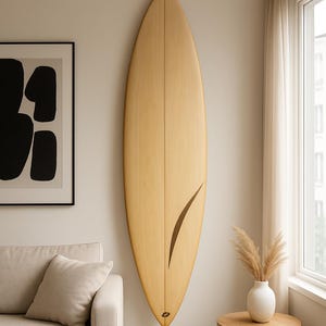 Peut inclure: Une planche de surf en bois clair avec un motif incurvé marron foncé est fixée au mur. La planche de surf est affichée verticalement. La pièce a une palette de couleurs neutres avec un canapé, des œuvres d'art et une petite table d'appoint.