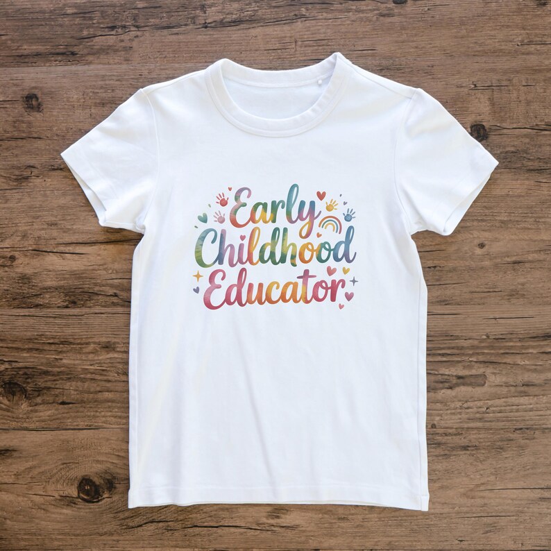 May include: White t-shirt featuring the words "Early Childhood Educator" in a vibrant, multi-coloured design. The design includes handprints, hearts, and a rainbow. The shirt is made of a soft material.