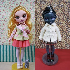 May include: Two fashion dolls are displayed. One doll has long blonde hair, a pink and green jacket, and a pink skirt. The other doll has black hair with a white streak, a white coat, and a plaid skirt. Both dolls are on stands.