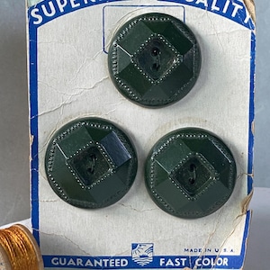May include: Three dark green circular buttons with a faceted square center and beaded border, mounted on a vintage cardboard display card labeled Superior Quality and Guaranteed Fast Color, Made in U.S.A., with a small spool of gold thread.