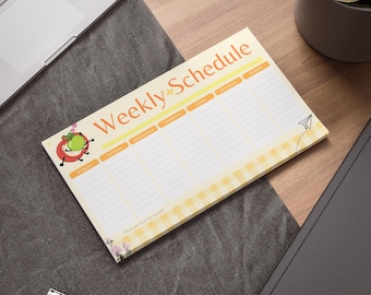 May include: A rectangular weekly schedule notepad with a light yellow background and a gingham border. The notepad features the words "Weekly Schedule" in orange and a cartoon apple character. Days of the week are listed across the top.