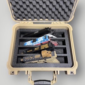 May include: Tan hard case with black foam inserts, holding several handguns. The handguns have various colors and designs, including a patriotic red, white, and blue pattern. The case is open, revealing the contents.