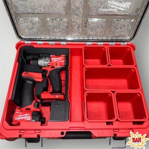 May include: Open red tool case with a clear lid, containing two red and black power tools. The case has multiple compartments and a handle. The brand name "Milwaukee" is visible on the tools. The lid is open, revealing the contents.