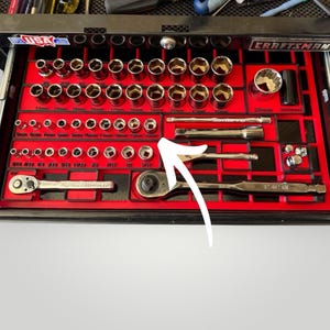 May include: A Craftsman tool set organized in a red tray within a black drawer. The set includes various sockets, extensions, and ratchets. Sizes are labeled in inches and millimeters. The drawer is marked with "USA" and "Craftsman".