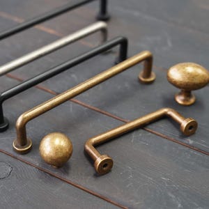 Peut inclure: Une collection de quincaillerie d'armoires avec des finitions variées, dont noir, argent et laiton antique. L'assortiment comprend des barres de tirage et des boutons ronds, pour les projets de décoration intérieure.