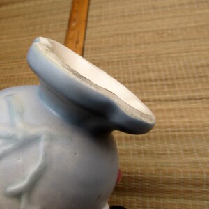 May include: A light blue ceramic vase with a floral design. The vase has a wide mouth and a narrow base.