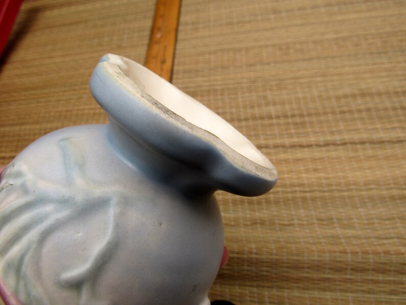May include: A light blue ceramic vase with a floral design. The vase has a wide mouth and a narrow base.