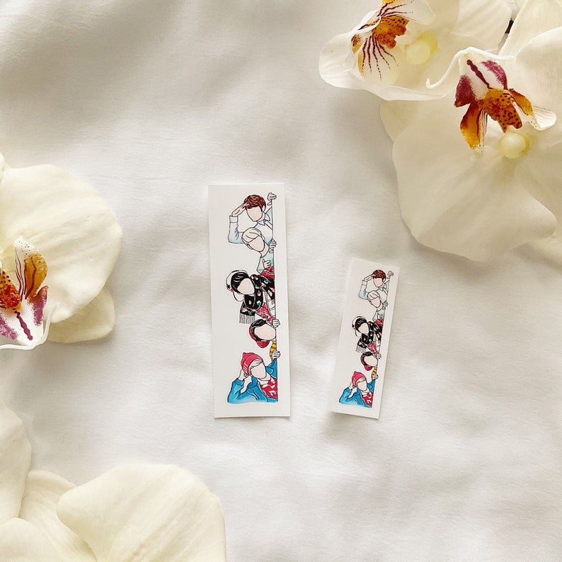 May include: Two white rectangular stickers with a watercolor illustration of people peeking from behind a wall. The stickers feature a line art style with pops of color, including red, blue, and black. The stickers are on a white background with white flowers.