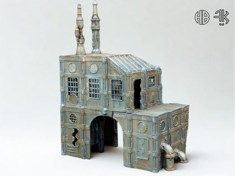 May include: A detailed miniature industrial building with a weathered, metallic finish. The model features multiple levels, arched entryways, windows, and smokestacks. The building has a distressed, aged appearance, with pipes and other industrial details.
