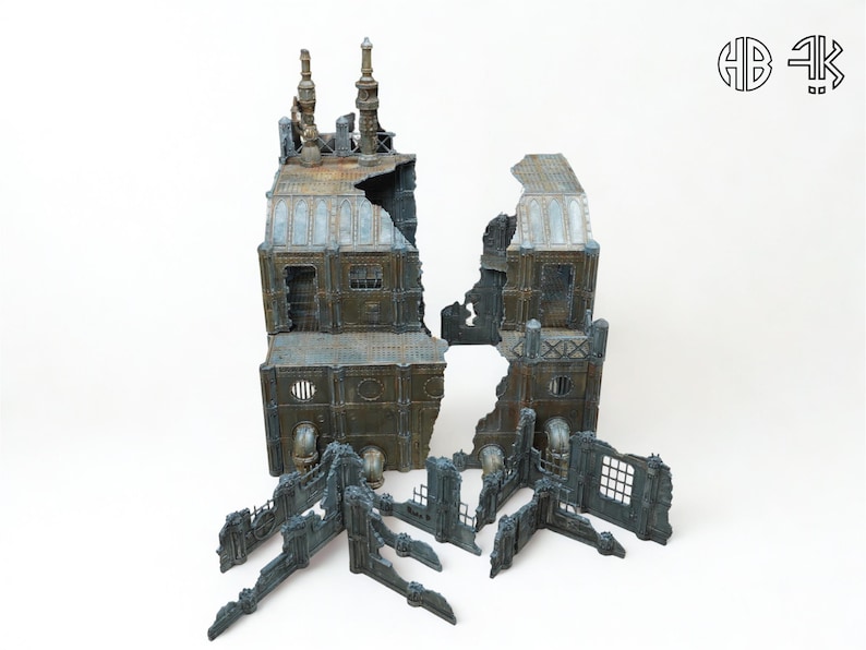 May include: A miniature, weathered, industrial building model, split into sections. The model features a distressed, metallic finish with blue and brown tones, and includes architectural details like chimneys and windows. The pieces are arranged on a white background.