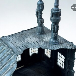 May include: A detailed, gray miniature building with a textured roof and decorative lampposts. The building has multiple windows and architectural details, suggesting a fantasy or sci-fi theme. The image is well-lit, highlighting the intricate design.