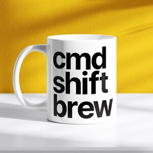 Könnte beinhalten: Weiße Keramiktasse mit schwarzem Text, der "cmd shift brew" lautet.