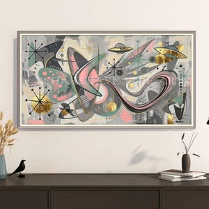 May include: A rectangular framed wall art piece featuring an abstract composition with boomerang shapes, starburst motifs, and flying saucer illustrations in shades of gray, pink, teal, and gold leaf accents on a light background.