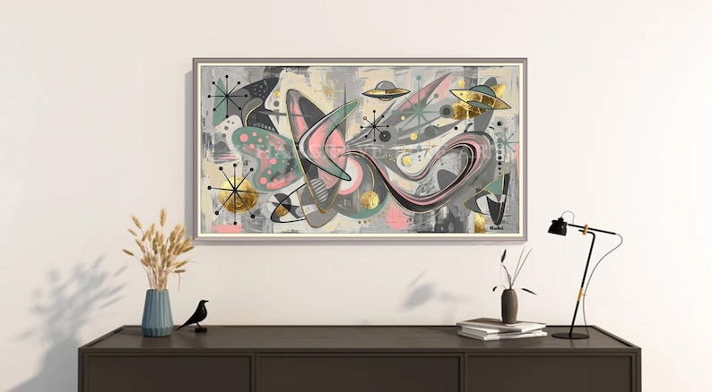 May include: A rectangular framed wall art piece featuring an abstract composition with boomerang shapes, starburst motifs, and flying saucer illustrations in shades of gray, pink, teal, and gold leaf accents on a light background.