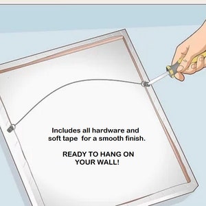 May include: A rectangular framed artwork with a white surface, a wire for hanging, and the text "READY TO HANG ON YOUR WALL!". The frame is silver and a hand is using a screwdriver to secure the wire.