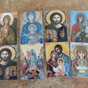 May include: Set of six religious icons featuring various depictions of Jesus, Mary, and angels. The icons are printed on paper and encased in clear plastic sleeves.