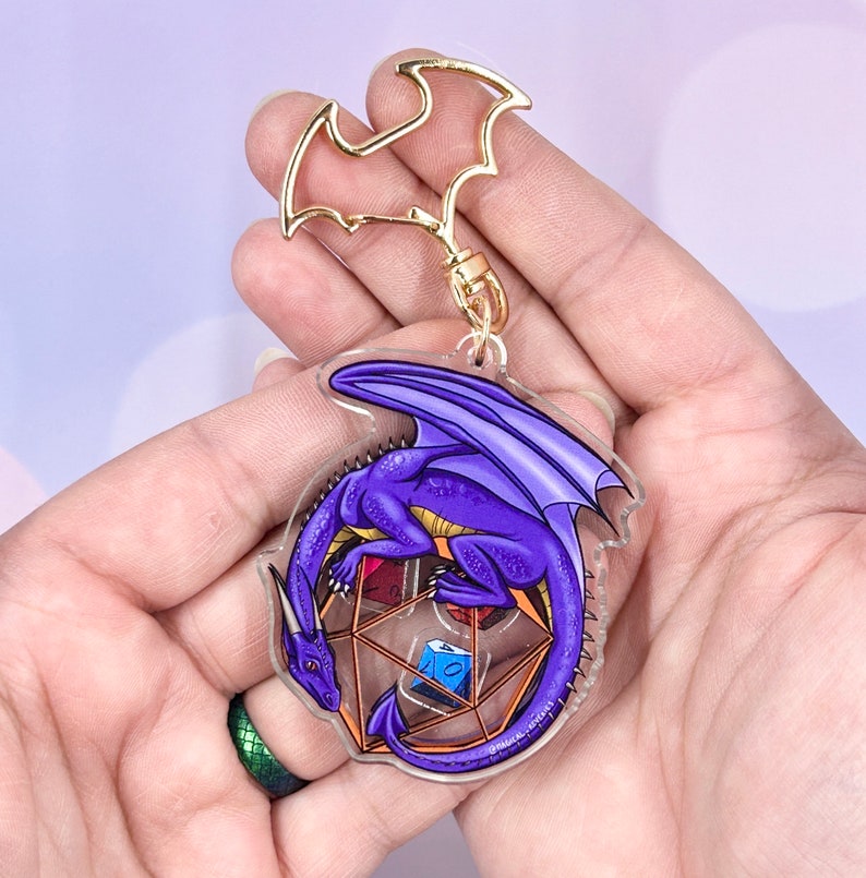 May include: Purple dragon keychain with gold accents, curled around a clear, multi-sided dice with red, blue, and green dice inside.