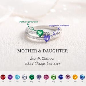 Puede incluir: Un anillo de plata con tres bandas, con piedras preciosas en forma de corazón en verde y morado. El anillo está adornado con pequeñas piedras transparentes. El texto "MOTHER & DAUGHTER" y "Time Or Distance Won't Change Our Love" se muestra debajo.