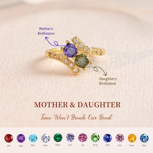May include: A gold ring featuring a purple and green gemstone, with smaller clear stones. The ring is inscribed with "Mother & Daughter" and "Time Won't Break Our Bond". A selection of birthstone colors is displayed below.
