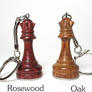 May include: Two wooden chess piece keychains, one in rosewood and one in oak. Both are queen pieces with silver key rings.