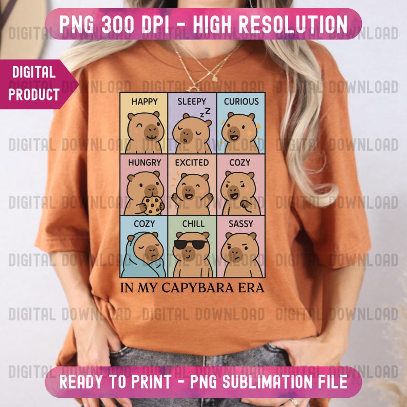 May include: An orange t-shirt featuring a grid of capybara illustrations, each depicting a different emotion, with text labels like "Happy" and "Sleepy." The phrase "IN MY CAPYBARA ERA" is printed below the grid.