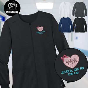 May include: Black embroidered medical jacket with a zipper closure. Features a pink heart design with a heartbeat and the text "JESSICA, BSN RN Cath Lab" in teal. Additional jackets in white, gray, navy, and black are also shown.