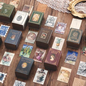 May include: An assortment of miniature book-shaped boxes and cards with a vintage theme. The boxes are labelled with titles such as "ANGELS ON EARTH" and "CHILD HOOD." The cards feature illustrations and text, evoking a sense of nostalgia.
